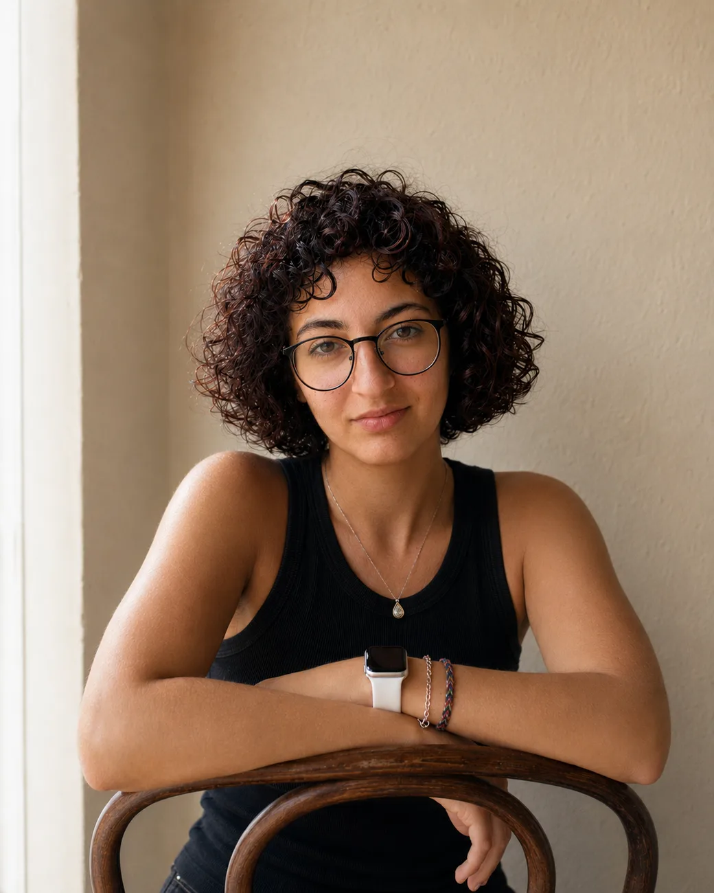 Zein, seated backwards on a bentwood chair with her arms crossed over its back, smiling calmly